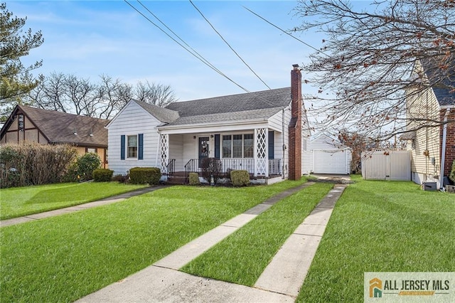 bungalow-style house featuring a porch, a garage, an outdoor structure, and a front yard