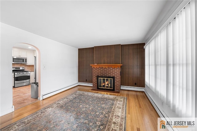 living room with a brick fireplace, light hardwood / wood-style flooring, and a baseboard radiator