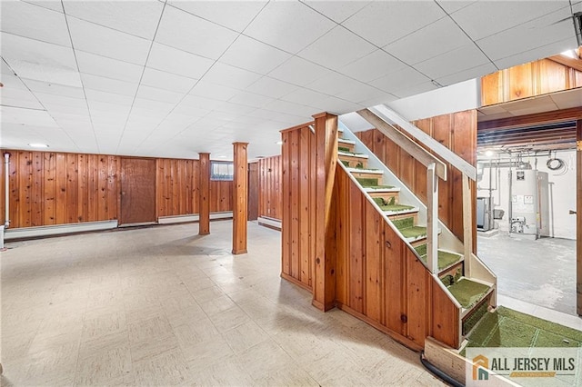 basement with wood walls, gas water heater, and baseboard heating