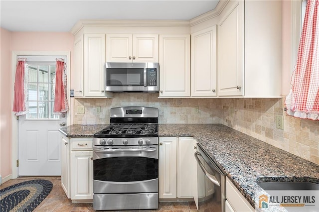 kitchen with backsplash, appliances with stainless steel finishes, and dark stone countertops