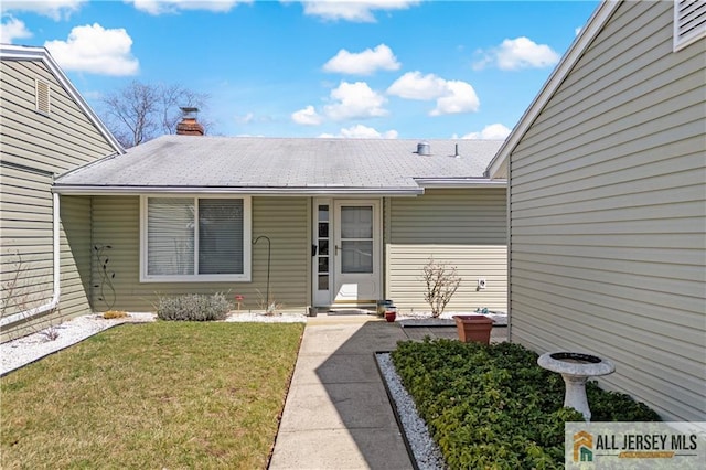 21 Celtis Plz Unit 21B, Monroe, NJ 08831 - view of exterior entry featuring a yard, a chimney, and a shingled roof