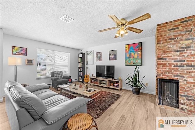 21 Celtis Plz Unit 21B, Monroe, NJ 08831 - living area with light wood-style flooring, a ceiling fan, baseboards, a brick fireplace, and a textured ceiling
