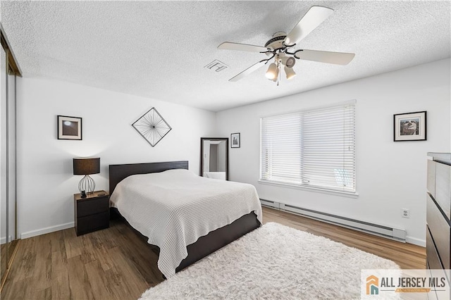 21 Celtis Plz Unit 21B, Monroe, NJ 08831 - bedroom with a baseboard heating unit, wood finished floors, a textured ceiling, a ceiling fan, and baseboards