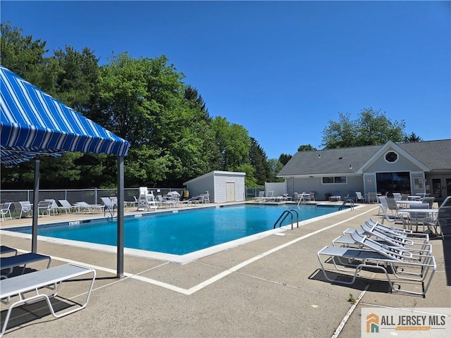 115 Griggs Pl Unit 115, East Brunswick, NJ 08816 - community pool featuring a patio area, an outdoor structure, and view of scattered trees