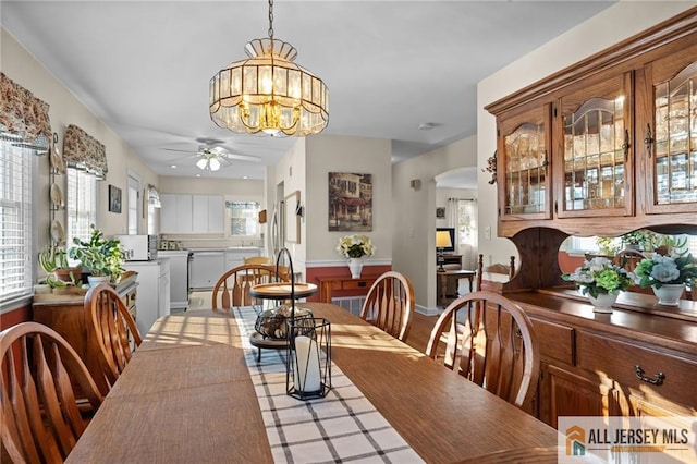 dining room with arched walkways and ceiling fan with notable chandelier