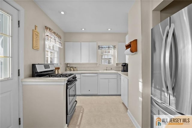 kitchen featuring appliances with stainless steel finishes, white cabinetry, light countertops, and a sink