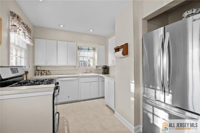 kitchen with a sink, stainless steel appliances, white cabinets, and light countertops