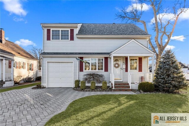 view of front of home with decorative driveway, covered porch, roof with shingles, an attached garage, and a front yard