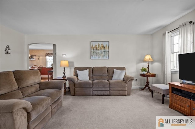 living room featuring arched walkways and light colored carpet