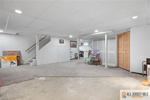 finished basement featuring a drop ceiling, recessed lighting, and stairs