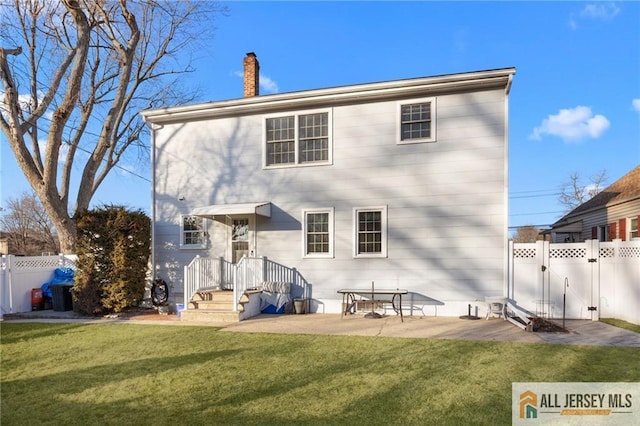 back of property with a gate, a patio, fence, a yard, and a chimney