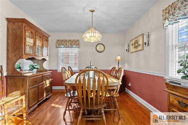 dining area featuring an inviting chandelier, baseboards, and dark wood-style flooring