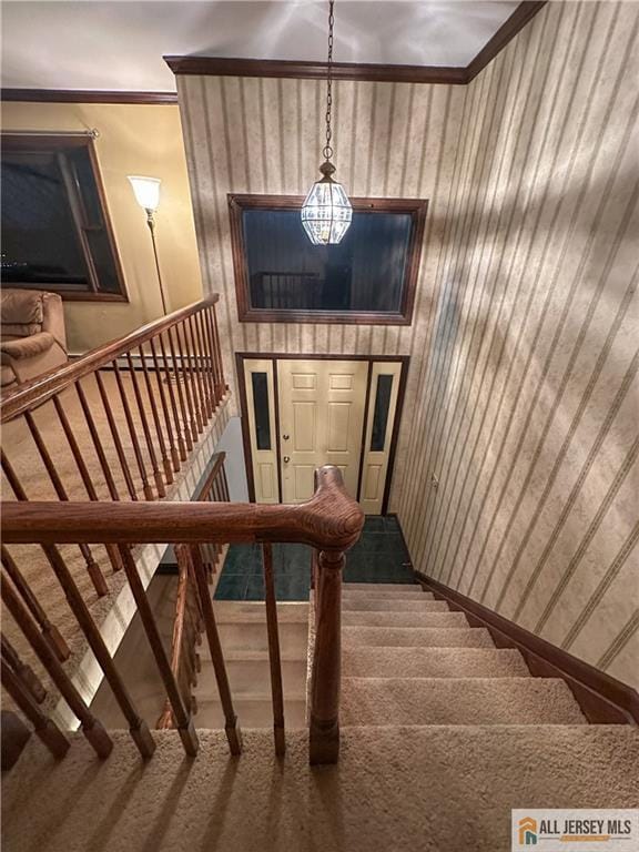 stairs featuring carpet flooring, ornamental molding, and wood walls