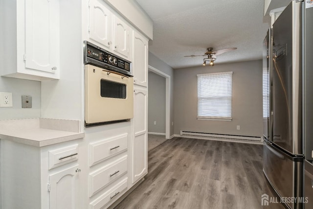 474 Revere Way Unit N, Monroe, NJ 08831 - kitchen featuring freestanding refrigerator, oven, a baseboard heating unit, light countertops, and white cabinetry