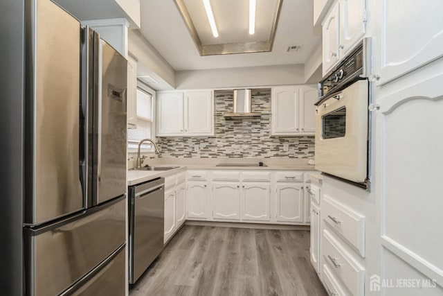 474 Revere Way Unit N, Monroe, NJ 08831 - kitchen with appliances with stainless steel finishes, a sink, wall chimney exhaust hood, white cabinets, and light wood-style flooring