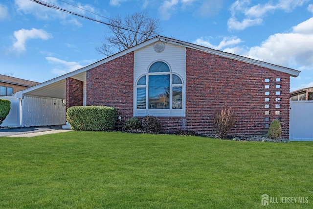 exterior space featuring brick siding, a carport, a front yard, and fence