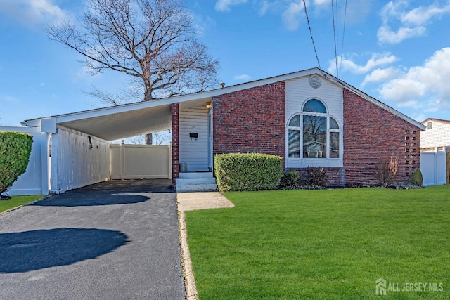 mid-century inspired home with brick siding, a front lawn, fence, a carport, and driveway