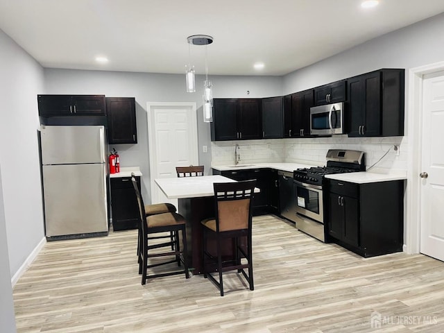 kitchen with sink, a kitchen island, decorative light fixtures, stainless steel appliances, and a breakfast bar area