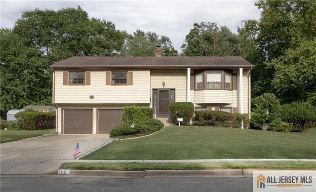 12 Tompkins Rd, East Brunswick, NJ 08816 - split foyer home with concrete driveway, an attached garage, and a front yard