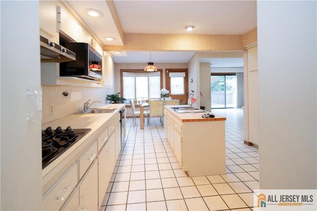 12 Tompkins Rd, East Brunswick, NJ 08816 - kitchen with white cabinets, range hood, light tile patterned floors, black gas stovetop, and pendant lighting