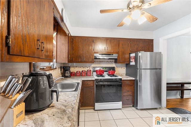 58 Stewart Pl S, Orange Village, NJ 07079 - kitchen with range with gas stovetop, freestanding refrigerator, a sink, under cabinet range hood, and light countertops