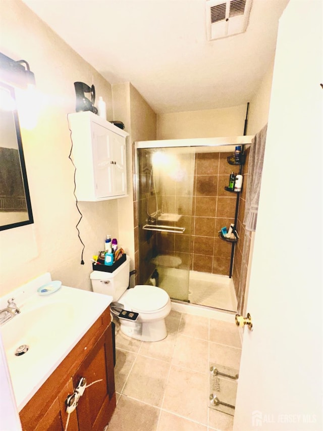 bathroom with an enclosed shower, vanity, tile patterned flooring, and toilet