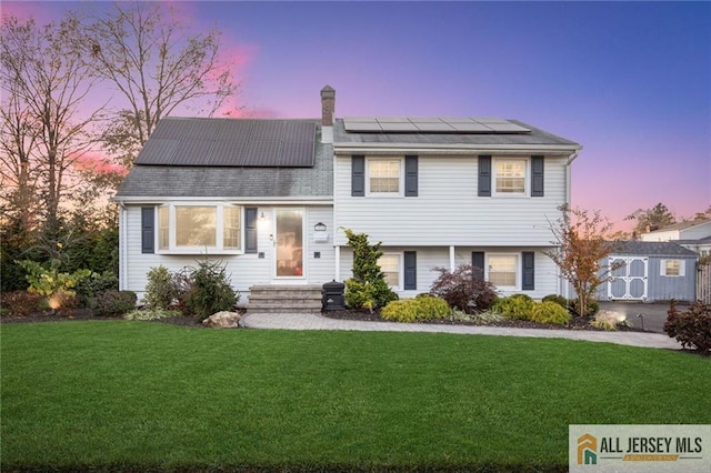 split level home featuring solar panels and a yard