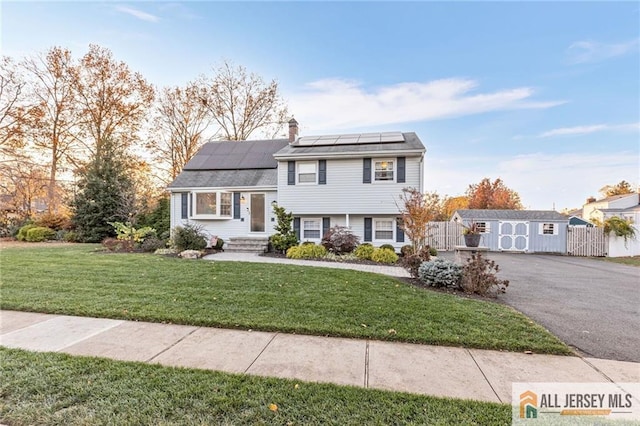 tri-level home with a storage shed, a front lawn, and solar panels