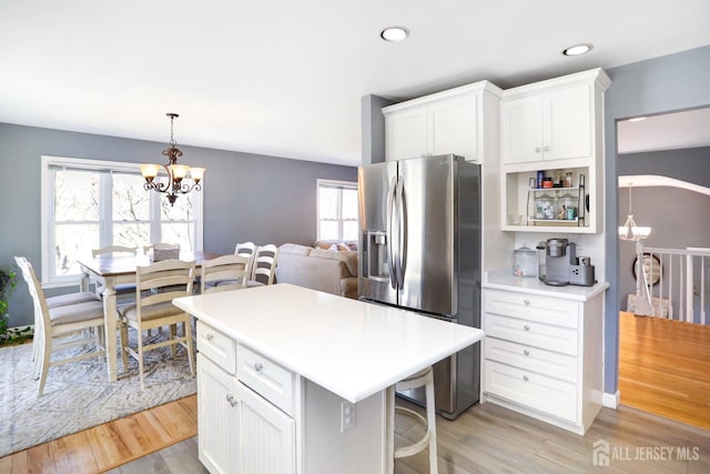 7 Arthurs Ct, Manalapan, NJ 07726 - kitchen with stainless steel fridge with ice dispenser, a chandelier, light wood-type flooring, white cabinetry, and a breakfast bar area