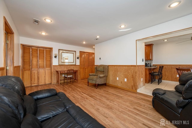 living area with recessed lighting, visible vents, wainscoting, and light wood-type flooring