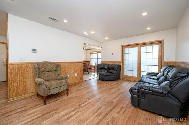 living area with visible vents, a wainscoted wall, wood walls, light wood-type flooring, and recessed lighting