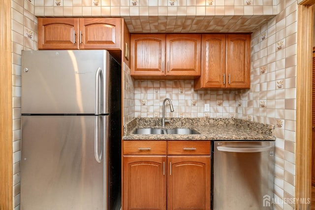 kitchen with light stone counters, brown cabinets, appliances with stainless steel finishes, and a sink