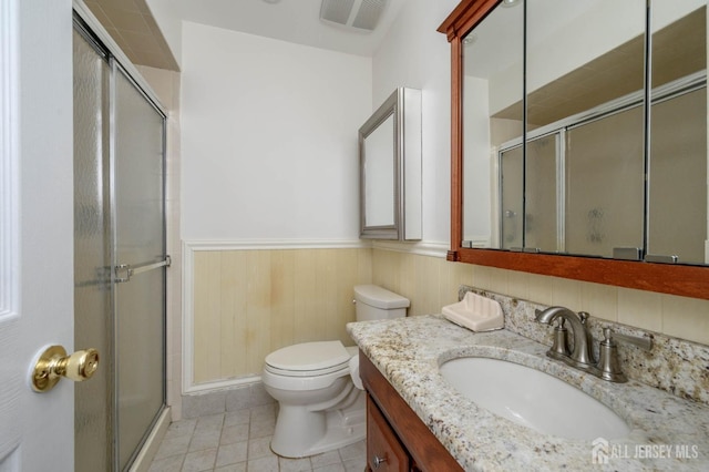 bathroom with a wainscoted wall, toilet, visible vents, and a stall shower