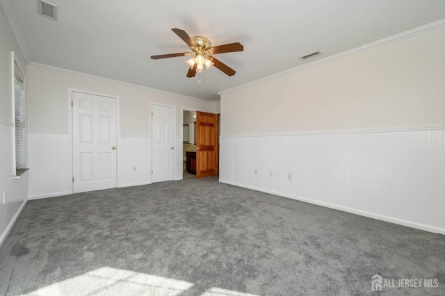 unfurnished bedroom with visible vents, carpet flooring, ornamental molding, and wainscoting