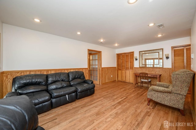 living room featuring visible vents, a wainscoted wall, recessed lighting, light wood-style floors, and wood walls