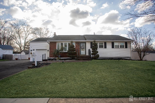 ranch-style home featuring brick siding, a front lawn, fence, aphalt driveway, and an attached garage