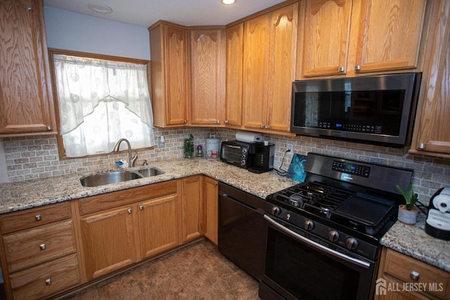 kitchen with a sink, stainless steel appliances, light stone countertops, and tasteful backsplash