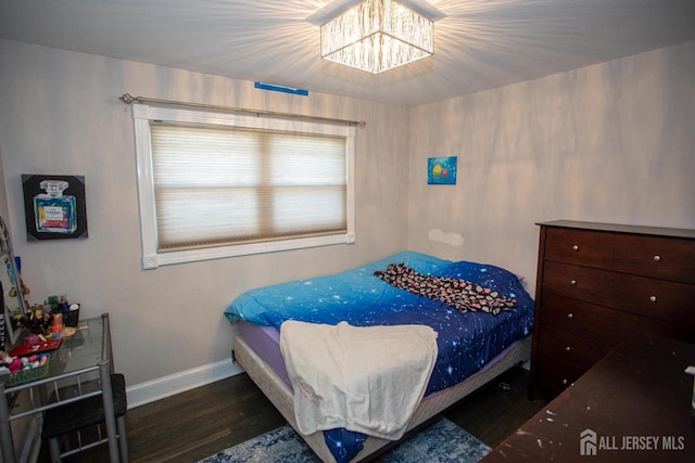 bedroom with baseboards, an inviting chandelier, and wood finished floors