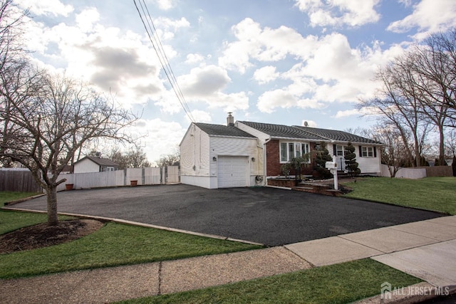 single story home featuring driveway, fence, a front yard, an attached garage, and a chimney