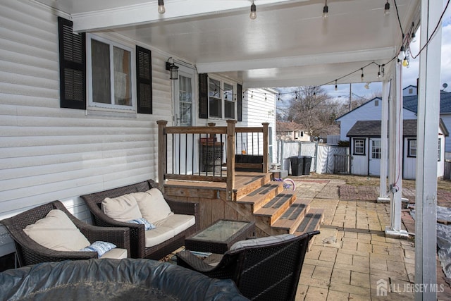 view of patio / terrace featuring a storage unit, an outdoor hangout area, an outbuilding, and fence