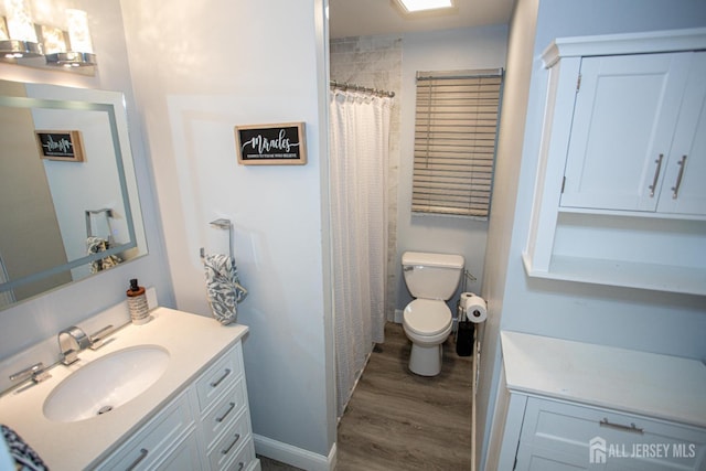 bathroom with curtained shower, toilet, wood finished floors, and vanity