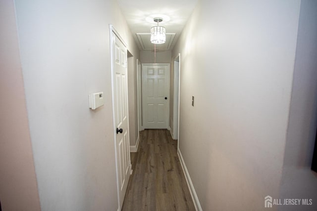 hall with baseboards, attic access, and wood finished floors