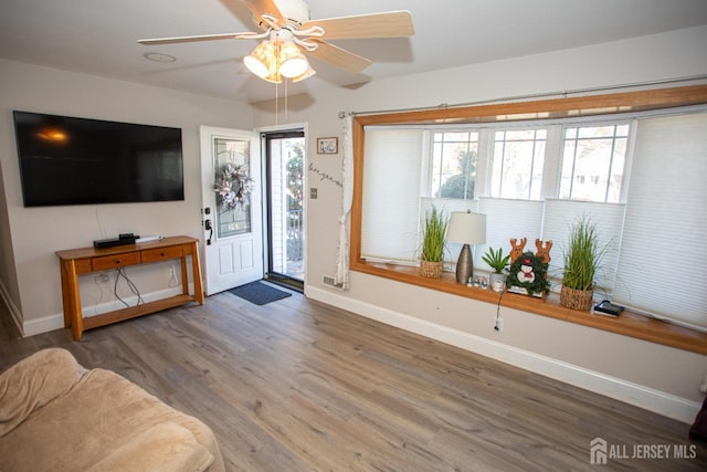 entrance foyer with a ceiling fan, wood finished floors, a healthy amount of sunlight, and baseboards