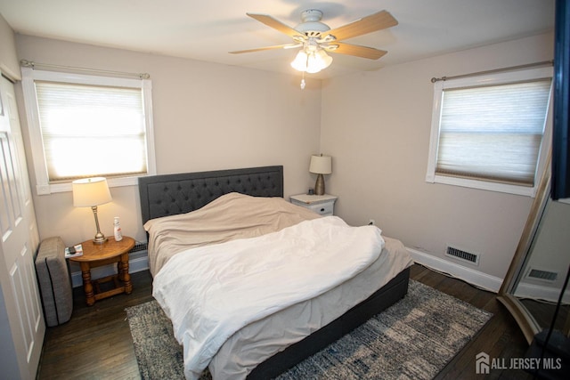 bedroom with multiple windows, wood finished floors, visible vents, and baseboards