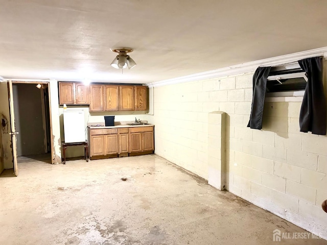 kitchen with concrete flooring, concrete block wall, and brown cabinets