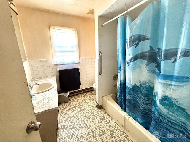 bathroom featuring shower / bath combo, a wainscoted wall, tile patterned flooring, vanity, and tile walls