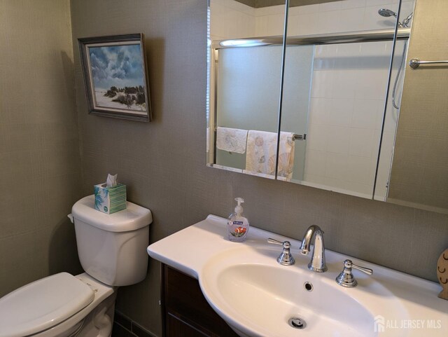 bathroom with vanity, a shower with shower door, and toilet