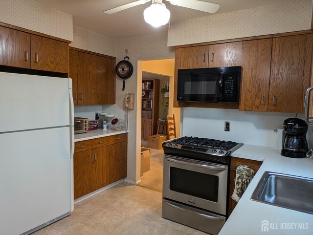 kitchen with sink, stainless steel range with gas cooktop, ceiling fan, and white refrigerator