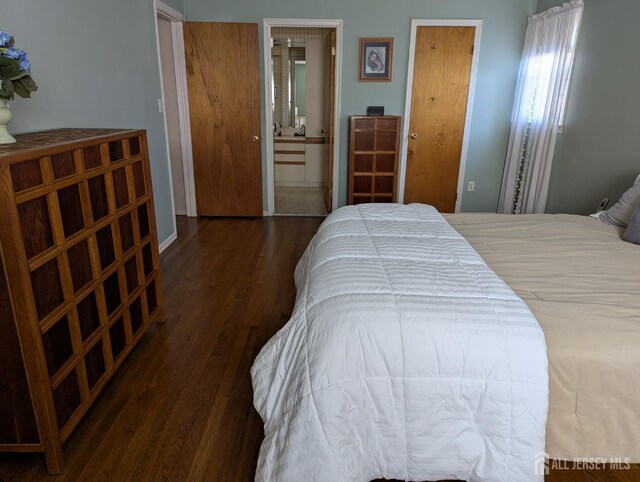 bedroom with dark wood-type flooring and connected bathroom