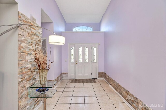 foyer entrance with light tile patterned flooring and a high ceiling